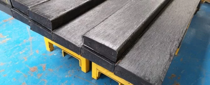 brown recycle plastic wood on a yellow stand ready to be packaged up and sent out 