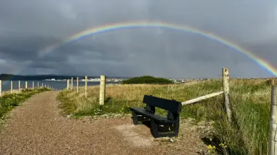 Bench under a vibrant rainbow arch. British Recycled Plastic
