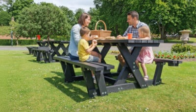 Family picnic at a park around a British Recycled Plastic Batley Walkthrough Picnic Table