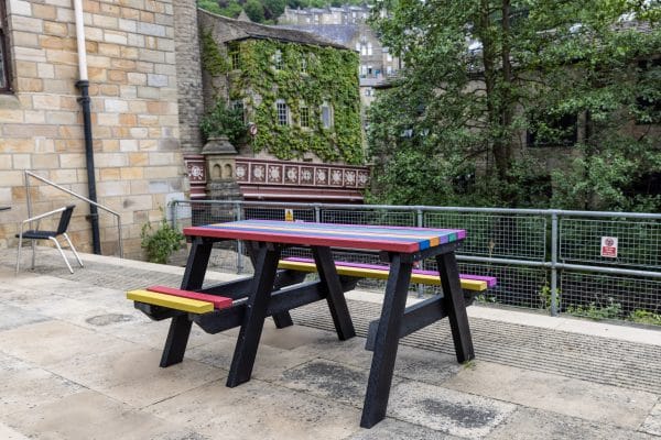 A rainbow coloured Bradshaw wheelchair accessible recycled plastic picnic table, donated to Hebden Bridge Community Association to celebrate Pride Week in 2021.