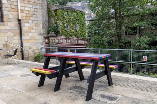 A rainbow coloured Bradshaw wheelchair accessible recycled plastic picnic table, donated to Hebden Bridge Community Association to celebrate Pride Week in 2021.