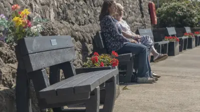 Two women sitting on benches outdoors. British Recycled Plastic