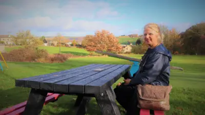 Woman sitting at picnic table outdoors. British Recycled Plastic