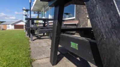 Black benches outside a building. British Recycled Plastic