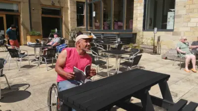 Man in wheelchair at picnic table. British recycled Plastic