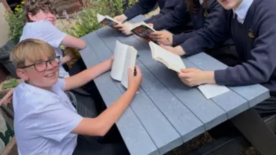 Students reading together at picnic table. British Recycled Plastic