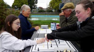 People playing noughts and crosses outdoors at an otley picnic table