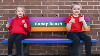 Children smiling on colourful buddy bench. British-Recycled-Plastic