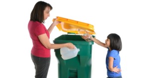 Parent teaching sustainability to kids with recycling bin