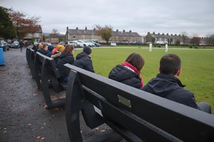 bench-Harewood-black-recycled-plastic-bench-people-watching-cricket-cold People sat at a sports ground on British Recycled Plastic Harewood Benches