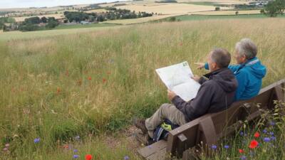 a couple reading a map looking at the coutryside on a British Recycled Plastic Harewood Bench