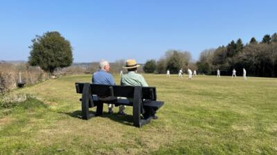 2 Men sat at a British Recycled Plastic Harewood Bench looking at field