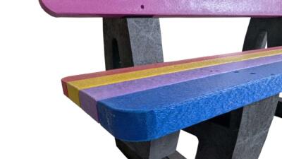 A bright, welcoming Buddy Bench made from recycled plastic, placed in a school playground to encourage children to sit, talk, and make new friends