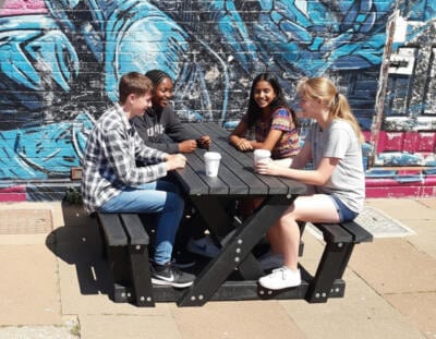 Four teenagers seated at a British Recycled Plastic Batley Walkthrough Picnic Table .
