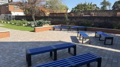 Outdoor seating area of a school with blue benches. British Recycled Plastic