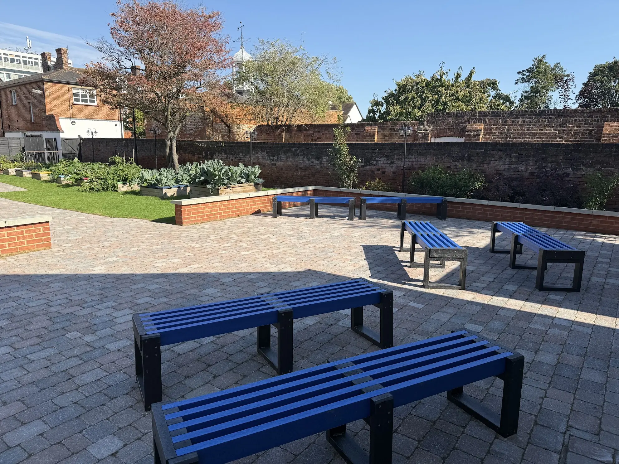 Outdoor seating area of a school with blue benches. British Recycled Plastic