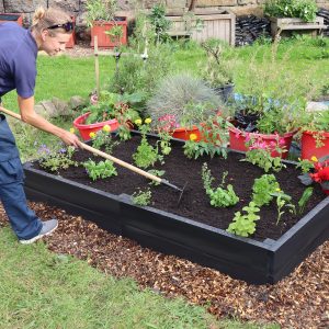 Martyna tending to a 2 metre x 1 metre recycled plastic raised bed, available with a 25 year guarantee from our webshop