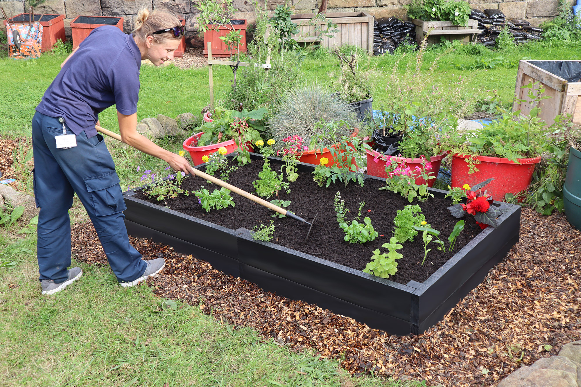 Martyna tending to a 2 metre x 1 metre recycled plastic raised bed, available with a 25 year guarantee from our webshop