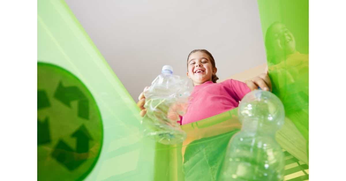 A child putting a plastic bottle into a recycling container