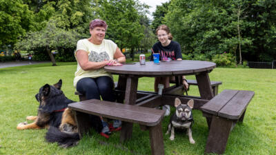 People sitting at a Calder recycled plastic picnic table at Moors Bank Park, Bolton with their dogs