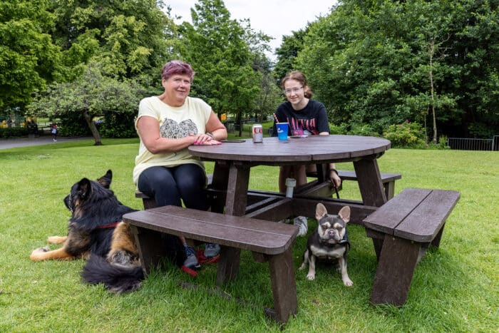 People sitting at a Calder recycled plastic picnic table at Moors Bank Park, Bolton with their dogs