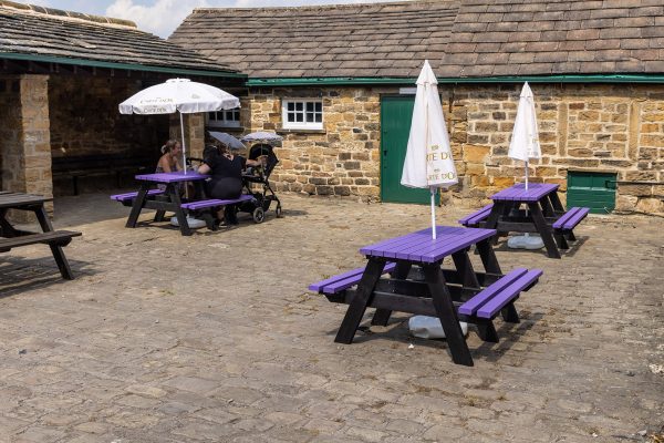 The Denholme classic adult A-frame picnic table with a purple top and seats at Worsbrough Mill