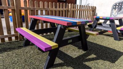 The Holmfirth junior recycled plastic A-frame picnic table with rainbow tops and seats at Kirkham and Wesham Primary School, suitable for infant and junior schools
