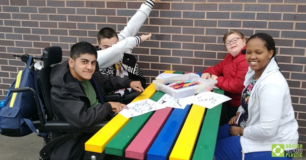 4 young adults sat at brightly colours recycled plastic picnic table 