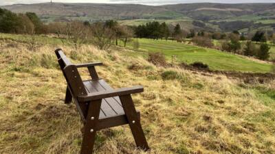 An Ilkley recycled plastic brown bench. Placed over looking the Calder valley.