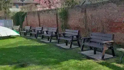 5 recycled plastic benches inside a walled garden