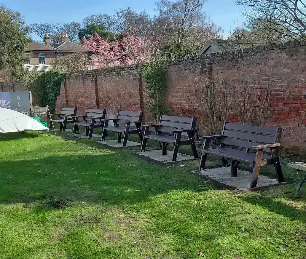 5 recycled plastic benches inside a walled garden