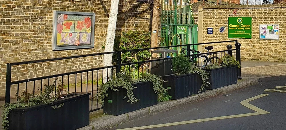 the drop off entrance to goose green school with recycled plastic planters being planted with specific plants to lower carbon emissions and improve air quality for children at the school