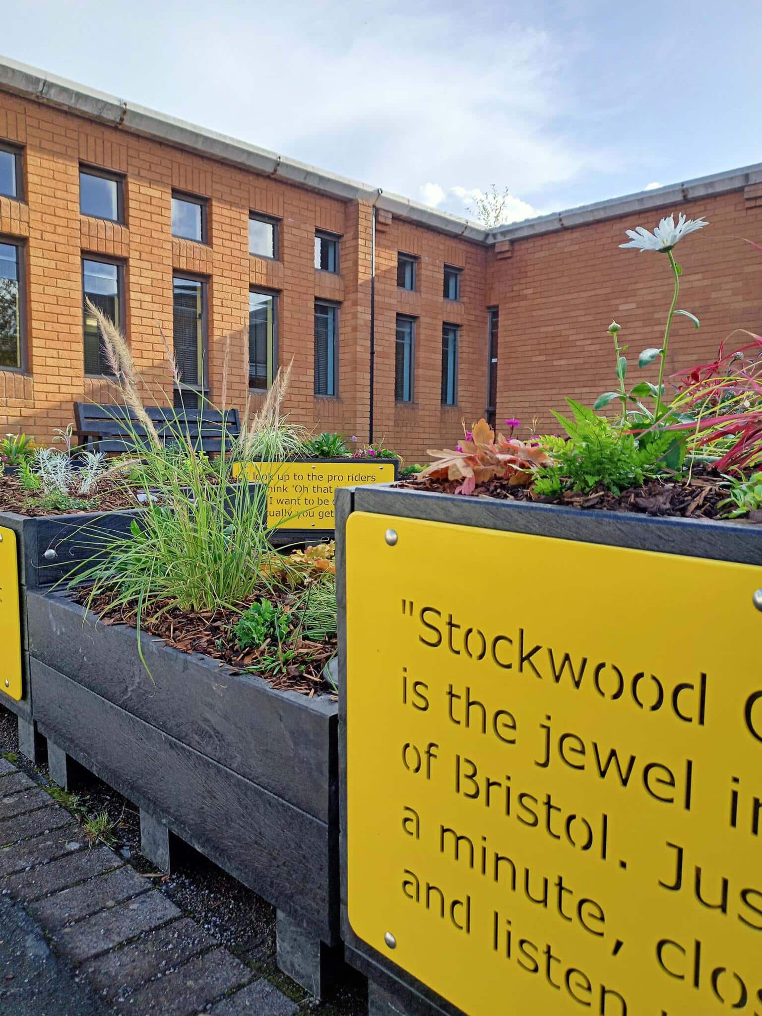 Modular parklet of artificial lumber on an urban high street, with a building and bench in the background