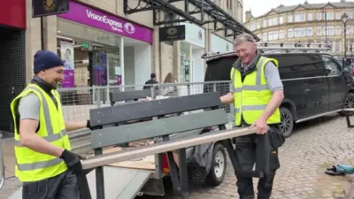 Two workers lifting a bench. British Recycled Plastic