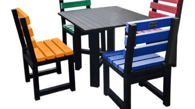 Black square table with multi-coloured chairs (orange, green, red, and blue) made from recycled plastic.