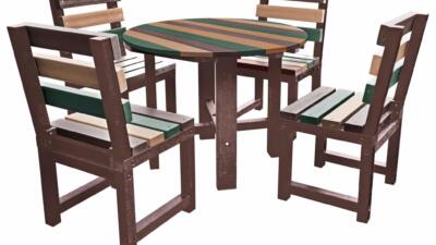 Black round table with multi-coloured chairs (orange, green, red, and blue) made from recycled plastic.