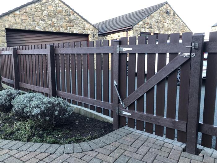 Fence 1 Brown fence made from artificial lumber in a residential garden with a garage in the background