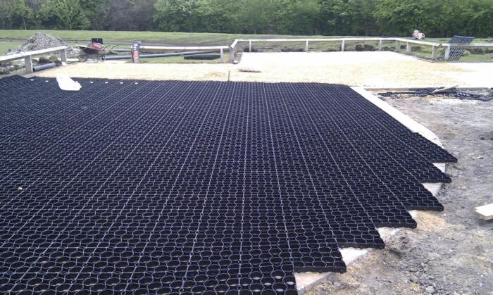 Hebden Everday Grid before infill Permeable ground reinforcement grids being installed in a car park, with gravel and greenery in the background.