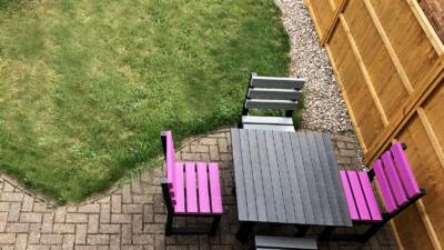 2 purple chairs and 2x grey chairs in a back garden with a square recycled plastic table