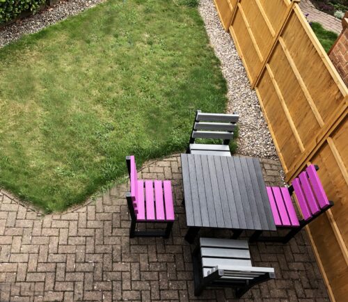 2 purple chairs and 2x grey chairs in a back garden with a square recycled plastic table