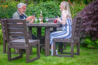 family of four dining outdoors at a brown recycled plastic table with brown chairs.