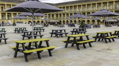 Yellow and green recycled plastic sustainable picnic tables in the courtyard of the Piece Hall in Halifax, a mecca for independent shops famous across the North.