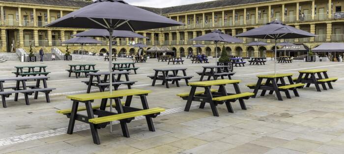 Yellow and green recycled plastic sustainable picnic tables in the courtyard of the Piece Hall in Halifax, a mecca for independent shops famous across the North. Yellow and green recycled plastic sustainable picnic tables in the courtyard of the Piece Hall in Halifax, a mecca for independent shops famous across the North.