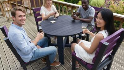 friends sat round a British Recycled Plastic round Featherstone dining set