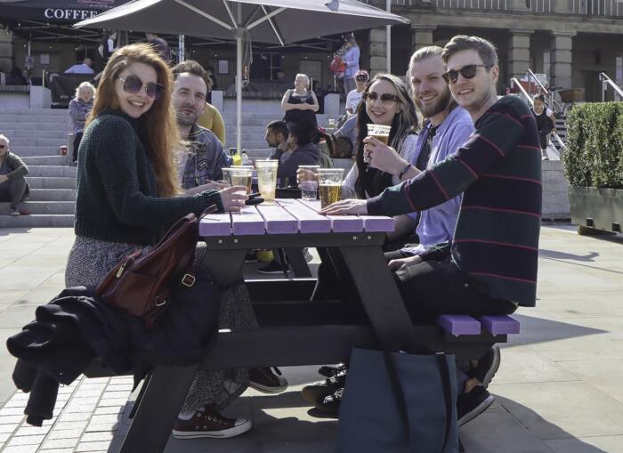 People enjoying a drink at a Denholme picnic table from British Recycled Plastic at the Piece Hall in Halifax, West Yorkshire. the best alternative for composite picnic tables