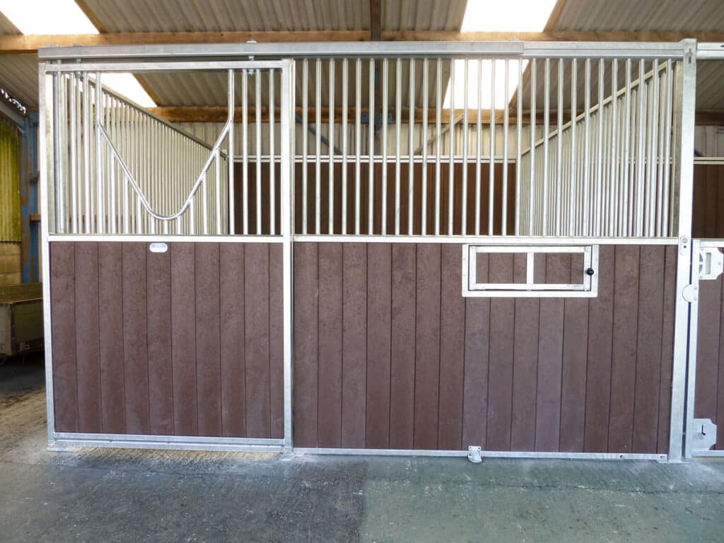 a brown and white artificial lumber stable made with wood from british recycled plastic