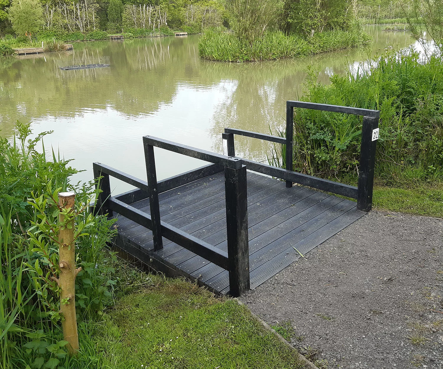 British Recycled Plastic black artificial lumber decking for a fishing peg. Next to a lake. side view