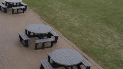 Grey and black recycled plastic picnic tables on paved area in a school