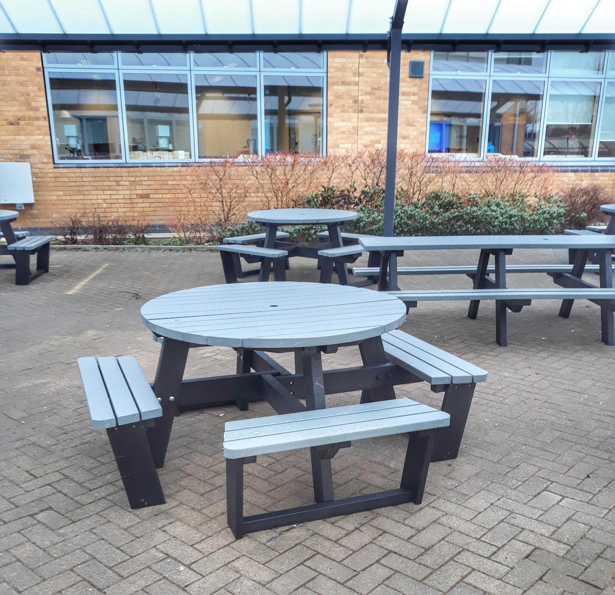 Grey British recycled plastic round picnic tables in a hospital grounds