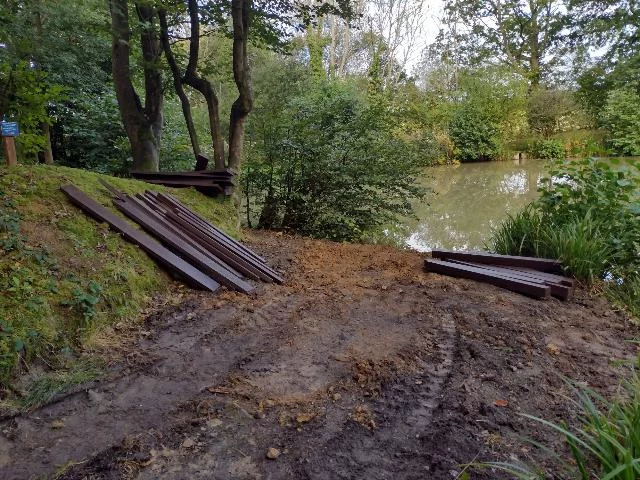 Construction of two fishing platforms on a small lake surrounded by lush green foliage.